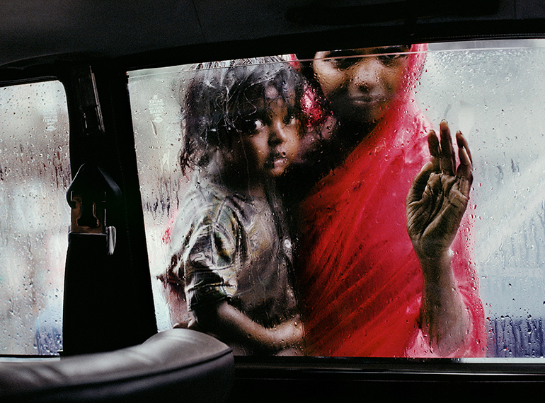 Madre con bambino che guardano dal finestrino all’interno di un taxi. India, Bombay (1993)